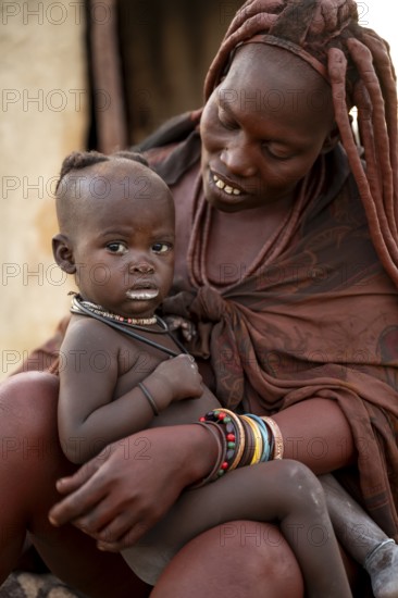 Baby in the arms of a Himba woman, traditional Himba village, Kaokoveld, Kunene, Namibia