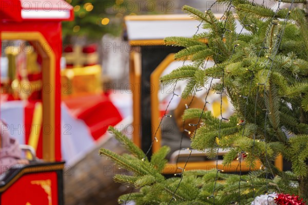 A decorated Christmas tree with lights next to a brightly decorated toy train, Sindelfingen, Böblingen district, Germany