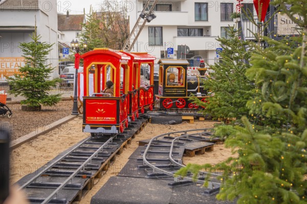 Children ride on a small toy train on tracks outside, Sindelfingen, Böblingen district, Germany