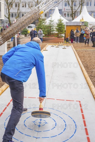 Man wearing a blue jacket playing curling on an outdoor course, Sindelfingen, Böblingen district, Germany