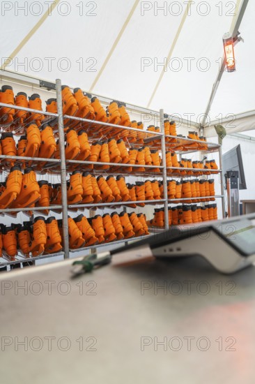 A tent with several shelves full of orange boots and a heater on the wall, Sindelfingen, Böblingen district, Germany