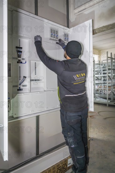 Technician working on a control cabinet, gloves, electrical cables, electrician, new building, Germany