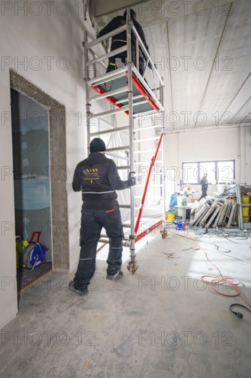 Worker on a construction site next to scaffolding, various construction works in the room, electrician, new building, Germany