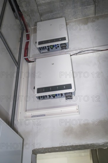 Two electronic devices are mounted on a wall, with visible cables and connections, electrician, Neubau, Germany