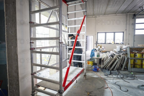 Interior on construction site with scaffolding, cables and building materials, lighting through windows, electrician, new building, Germany