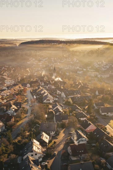Village bathed in warm sunshine, with light fog and church tower in an autumnal atmosphere, Gechingen, Hecken and GÃ¤u region, Calw district, Germany