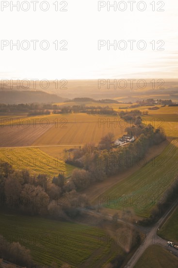 Wide landscape with fields and trees, under a soft, golden sunset, Gechingen, Hecken and GÃ¤u region, Calw district, Germany
