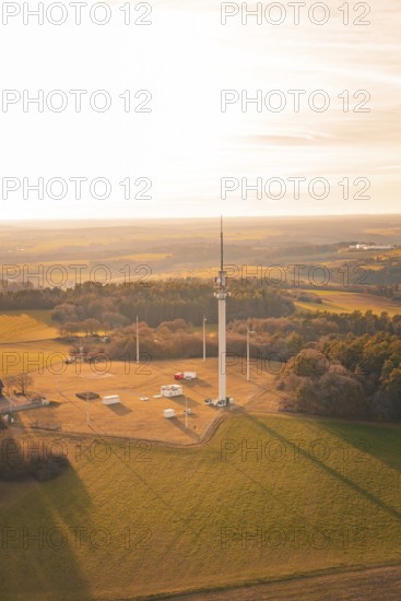 A radio tower stands in the middle of a large field, surrounded by forests at sunset, Gechingen, Hecken and GÃ¤u region, Calw district, Germany