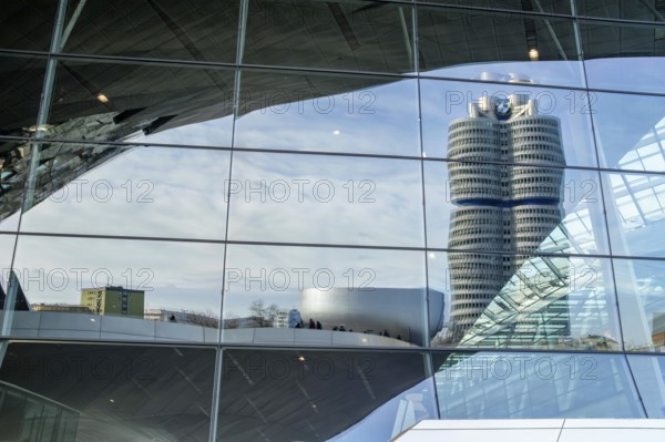 Reflected in the glass faÃ§ade of BMW Welt is the BMW high-rise building, also known as the BMW four-cylinder engine, it serves as the global corporate headquarters, headquarters of the car manufacturer BMW, Munich, Bavaria, Germany
