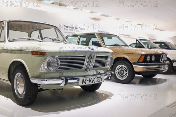 Classic BMW vehicles in the BMW Museum in Munich, In the foreground is a BMW 1600 built in 1966, it was the first vehicle of the legendary BMW 02 series, Behind it a BMW of the first 3 series (E21), which was introduced in 1975 and replaced the 02 series, Munich, Bavaria, Germany