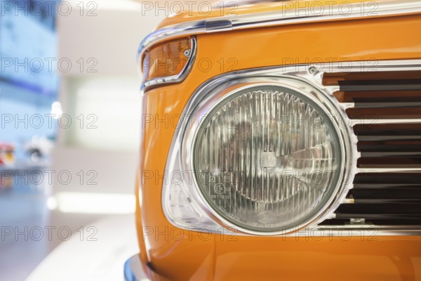 Detailed view, headlights of a BMW 02 series, 1502-2002tii, which was produced from 1966 to 1977. Color: The bright orange paint is often referred to as Inca orange and was a popular color for these models, BMW Welt, Munich, Bavaria, Germany