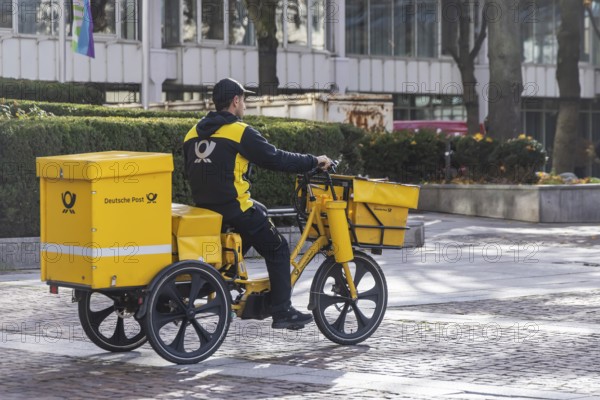Deutsche Post mailmen on a bicycle through the city. Stuttgart, Baden-WÃ¼rttemberg, Germany