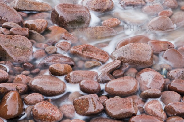 Detail of the swell on a red stone beach on the northwest coast of Scotland