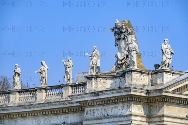 In the right half of the picture, large coat of arms of Pope Alexander VII next to statues of saints on the upper wreath of the faÃ§ade of St. Peter's Basilica, Vatican City, Vatican, Rome, Italy
