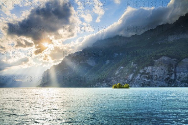 Evening sunshine on Lake Walensee with chive island near Mols, in turquoise water and SchÃ¤ren mountain range and Leistchamm in the background, Canton of St. Gallen, Switzerland