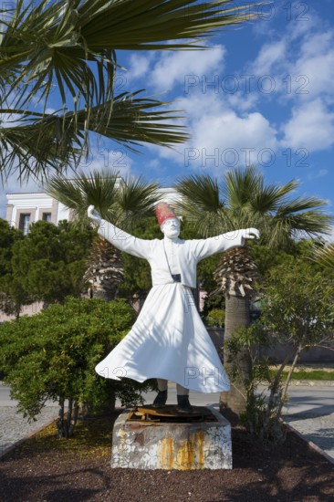 A white sculpture of a dancing man surrounded by palm trees under a clear sky, the swirling dervish, Alibey Adasi island, Cunda AdasÄ±, Ayvalik Islands, Ayvalik, Aegean Sea, Turkey
