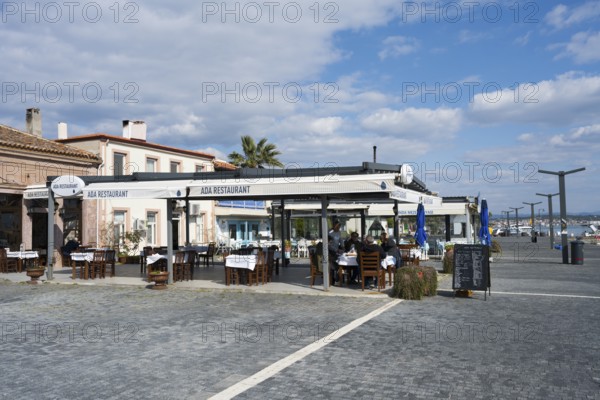 Seaside restaurant with outdoor seating area under blue and white skies, relaxed atmosphere and palm trees, Alibey, Alibey AdasÄ± Island, Ayvalik Islands, Aegean Sea, Turkey