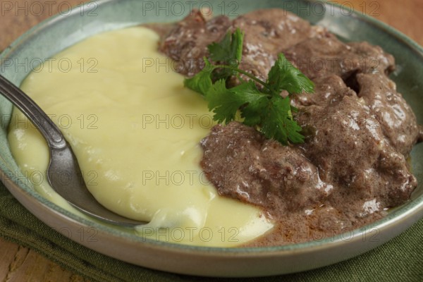 Liver beef stroganoff with mashed potatoes, table setting in green tones, homemade