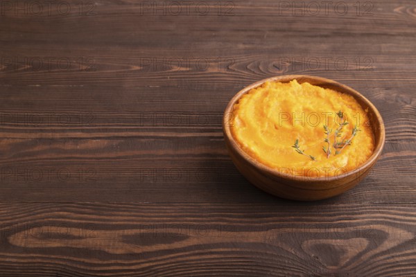 Sweet potato porridge in wooden bowl on wooden background. Diet, healthy eating concept. side view, copy space, minimalism
