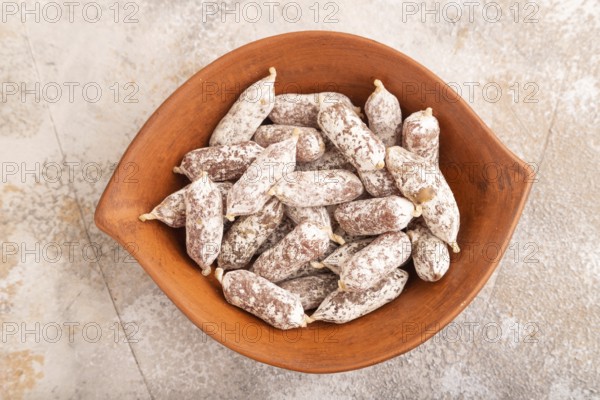 Small smoked Chicken sausages in clay bowl on brown concrete background. top view, close up