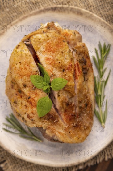 Fried Turkey Thigh with spices and rosemary on plate on brown wooden background and linen textile. side view, close up, selective focus