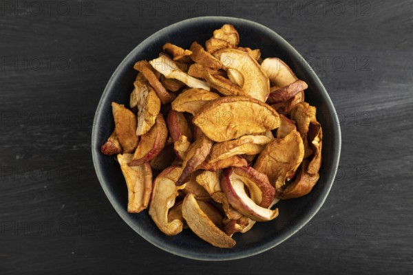 Dried Apples in ceramic bowl on black wooden background. Top view, close up, flat lay. healthy food, minimalism. sweet