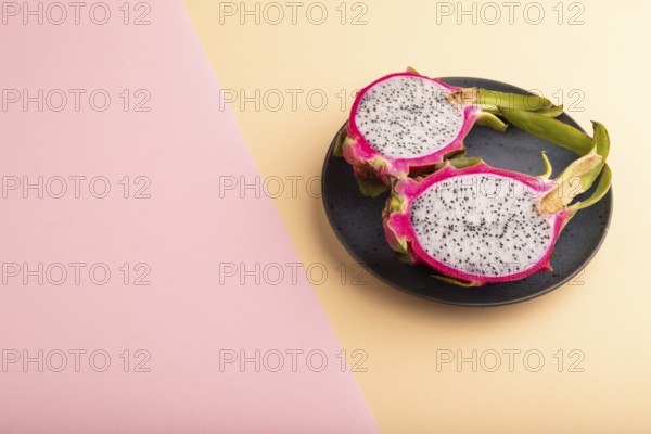 Ripe Pitaya on blue plate on pink and orange pastel paper background, side view, copy space, minimalism
