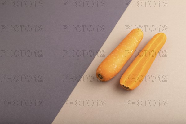 Orange Carrot on beige and gray pastel paper background. Side view, copy space, flat lay. healthy food, vegetable, minimalism