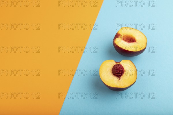 Peach Cut in half on orange and blue paper pastel background. Side view, copy space. healthy food, minimalism