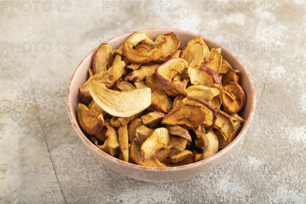 Dried Apples in ceramic bowl on brown concrete background. Side view, copy space, flat lay. healthy food, minimalism. sweet