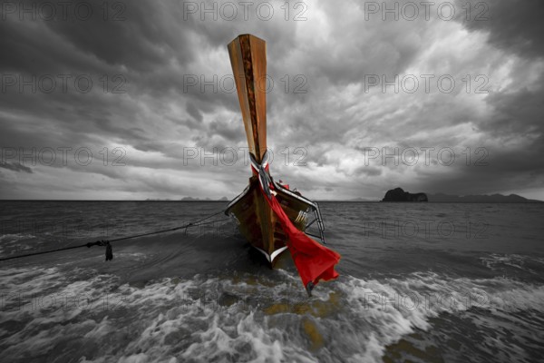 Longtail boat on the beach with dark rain clouds behind it, Koh Ngai island, Andaman Sea, Satun province, southern Thailand, Thailand