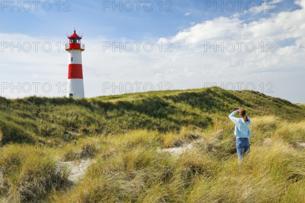 Young Fau takes a photo of the List-Ost lighthouse on his elbow on the island of Sylt, Germany