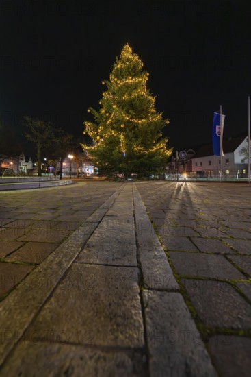 A festively lit Christmas tree at night on a paved square, Aidlingen, Böblingen district, Germany