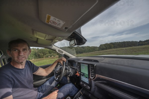 Young shepherd in car checks his flocks of sheep in nature reserves, Othenstorf, Mecklenburg-Western Pomerania, Germany