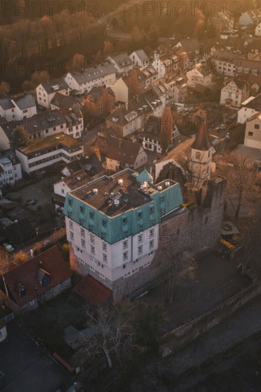 Aerial view of a village with a castle in warm evening light surrounded by trees, Dillweisenstein, Pforzheim, Germany