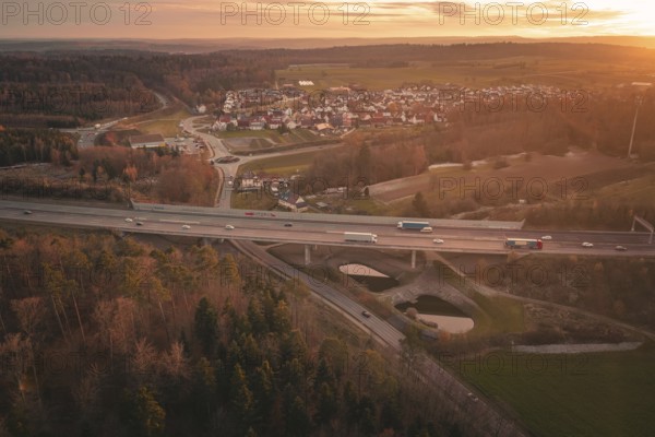Sunset over a rural village with a motorway leading through fields and forests, A8 motorway, Germany