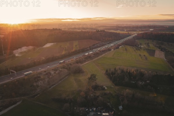 Highway in a vast landscape at sunrise, fields and forests in soft morning light, A8 motorway, Germany