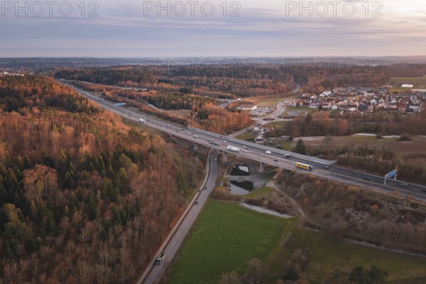 Aerial view of road junction in rural areas, lined with dense forest and visible traffic flow, A8 motorway, Germany