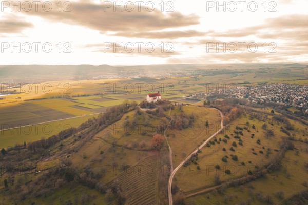 A hill with a church and a wide view over fields and a village under a cloudy sky, Wurmlinger Chapel, Rottenburg am Neckar, Germany