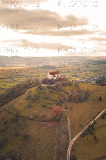 A hill with a church surrounded by vast fields under a dramatic sky, Wurmlinger Chapel, Rottenburg am Neckar, Germany