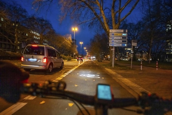 Cycling in the city, in the dark, in the evening, cycling on a bike lane, Huyssenallee, in front of Europaplatz, in downtown Essen, North Rhine-Westphalia, Germany