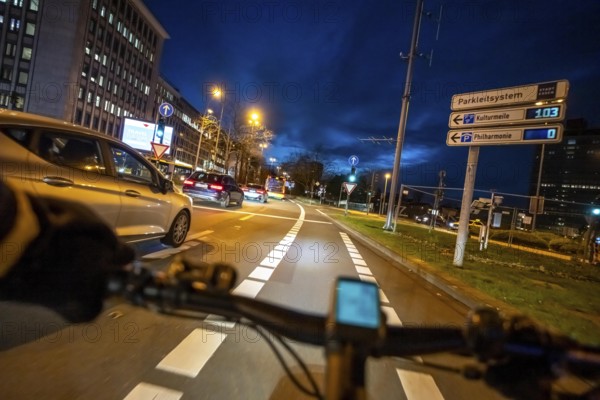 Cycling in the city, in the dark, in the evening, cycling on a bike lane, Huyssenallee, on Europaplatz, in downtown Essen, North Rhine-Westphalia, Germany