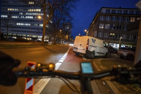 Cycling in the city, in the dark, in the evening, cycling on a bike lane, marked, delivery vehicle blocking the cycle path, Huyssenallee, in downtown Essen, North Rhine-Westphalia, Germany