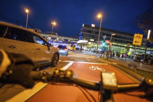 Cycling in the city, in the dark, in the evening, cycling on a bike lane, marked in red to alert drivers to the cycle path, between 2 lanes, Huyssenallee, in front of Europaplatz, in downtown Essen, North Rhine-Westphalia, Germany
