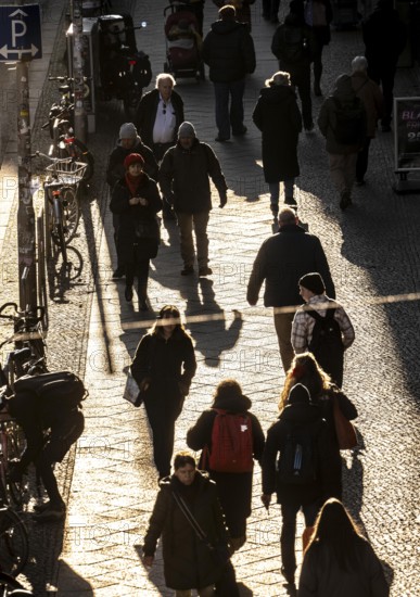 Passers-by on a FriedrichstraÃŸe sidewalk in Berlin, shade, low sun, winter, Germany