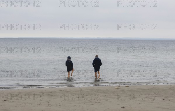 A couple standing barefoot in the cold seawater of the Baltic Sea, Scharbeutz, 28.11.2025, Scharbeutz, Schleswig-Holstein, Germany