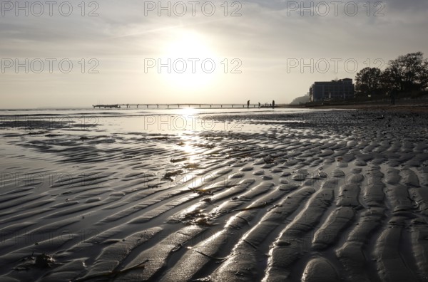 Low tide, wave and ripple patterns in wet sand, long pier in the background, sunrise, Scharbeutz, 29.11.2025, Scharbeutz, Schleswig-Holstein, Germany
