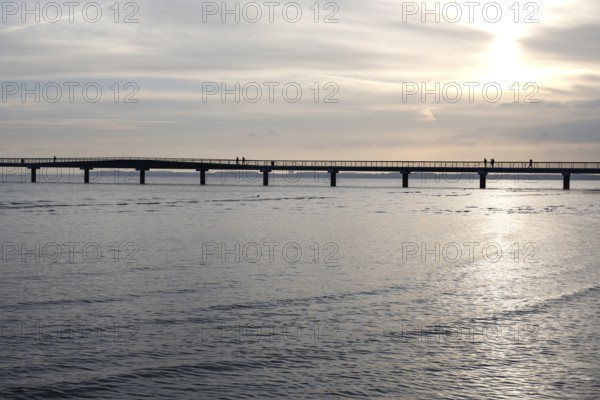 Silhouettes of people on a pier, sunrise, Scharbeutz, 29.11.2025, Scharbeutz, Schleswig-Holstein, Germany