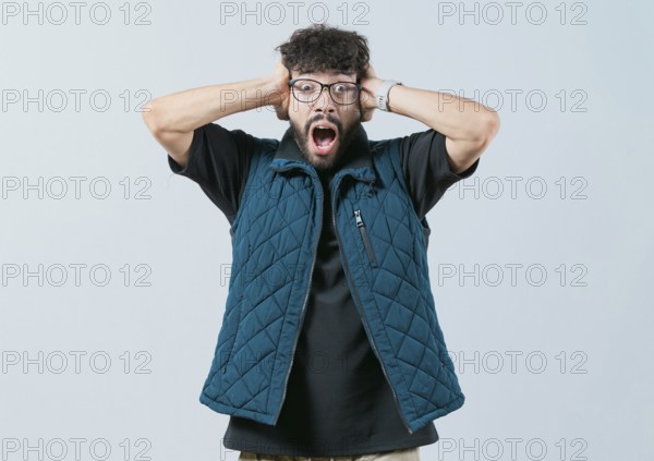 Panicked young man holding her head isolated. Worried and alarmed man holding her head
