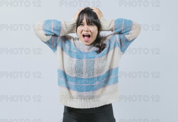 Panicked Asian girl holding her head isolated. Alarmed and worried woman holding her head